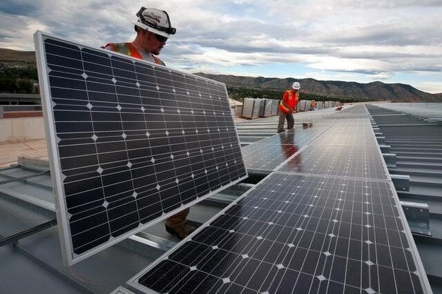 City workers installing solar panel on building