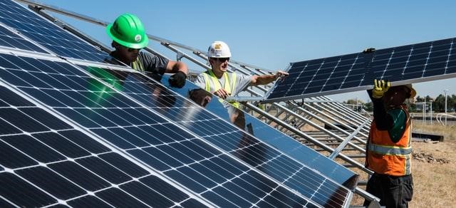 Workers putting on solar panels in a field